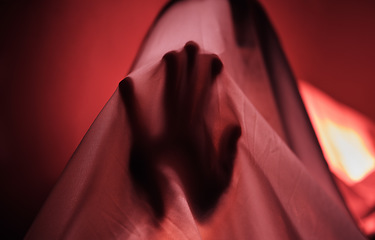 Image showing Hand, fabric and red with a person under a sheet in a bedroom or studio on a red background for psychology. Hands, silhouette and shadow with an adult struggling with mental health, anxiety or fear