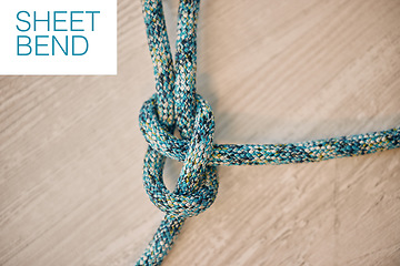 Image showing Hiking rope in a knot against a wooden floor background in a studio from above. Strong sheet bend tie, cable or cord equipment to secure safety while mountain climbing or extreme sports for athletes.