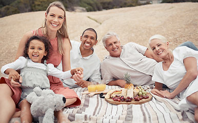 Image showing Portrait, love and happy interracial family having a picnic on the beach and smile while having some food with snacks. Bonding on a day out at the beach on tropical vacation holiday in summer