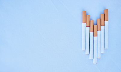 Image showing Cigarettes in a studio against a blue background mockup for cancer, toxic and addiction awareness. Cigarette, tobacco business and industry advertising for smoke, marketing and smoking market