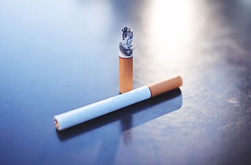 Image showing Smoking, tobacco and burning cigarette on table, close up of two cigarettes. Awareness for substance abuse, nicotine and unhealthy lifestyle addiction as cause for health issue, risk and lung cancer