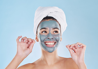 Image showing Skincare mask, hair care or dental floss in grooming, busy beauty and studio wellness on blue background. Smile, happy face or relax woman with mud product facial and cleaning teeth for healthy gums