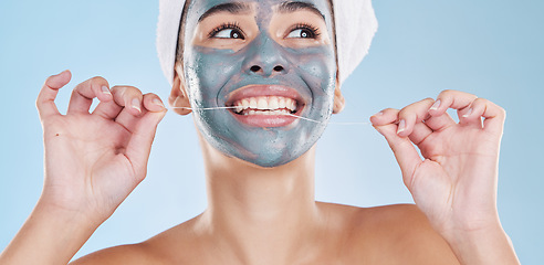 Image showing Dental, face mask and woman flossing teeth in a skincare beauty studio portrait with a blue background. Wellness, smile and happy girl grooming and cleaning her mouth and facial pores to be healthy