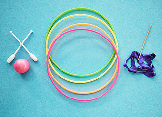 Image showing Gymnastics, dance and fitness with a hula hoop, ribbon and bars on an empty blue floor from above for exercise or training. Exercise, workout and still life with equipment for dancing or performance