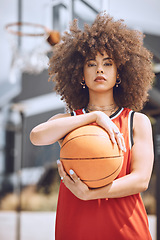 Image showing Portrait of a basketball player woman on a court holding a ball outdoors and ready for a sports competition. Trendy and serious African American woman athlete with cool wellness style or fashion