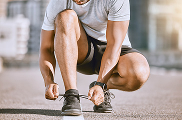 Image showing Feet of ready runner tying shoe lace for motivation and in fitness training in the city street, doing workout exercise for sport and for run in road in town. Active runner for wellness and exercising