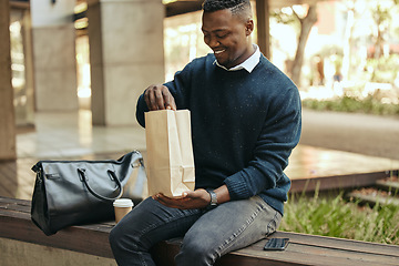 Image showing Office employee with a coffee, a paper sandwich bag and a smile, on a bench for a break from his busy work schedule. Happy, hungry businessman, time to eat, with his food and drink outside for lunch.