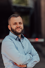 Image showing A successful young businessman in a shirt, with crossed arms, poses outdoors, confident expression on his face.