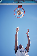 Image showing Basketball jump, goal and man on court playing a game low angle for mock up. Motivation, fitness and healthy lifestyle mindset of athlete. Dedicated sports person outside with a blue sky background.