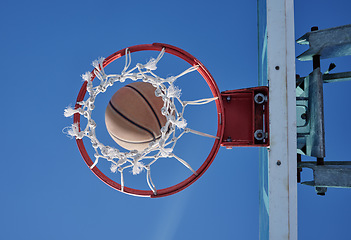 Image showing Basketball sports winner throwing, shooting hoops and slam dunk for points, score and performance during sports, competition and game match from below outdoor. Background of net, hoop and goal target