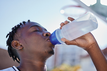 Image showing Water, hydration and healthy lifestyle of a sporty black man drinking water from a bottle, enjoying a refreshing drink. African athlete restore electrolytes while being active and exercise outside