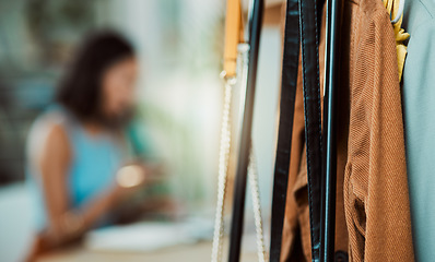 Image showing Fashionable clothes, wardrobe display and boutique collection hanging on store rail with designer, stylist and woman working in the background. Closeup of trendy clothing design in a creative startup