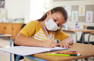 Image showing School, education and learning with covid mask on girl face in classroom, writing or doing assignment alone. A dedicated, smart and disciplined learner in a lesson during pandemic while taking notes