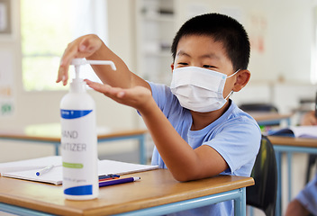 Image showing Covid, hand sanitizer and school student with mask cleaning, protecting and staying safe in education classroom. Small, little and cute asian boy in learning in study class preventing spread of virus