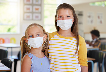 Image showing Young kids learning in classroom, after covid pandemic, wearing face masks together in school. Portrait of little girl students, waiting for their education lesson to begin, with their friends