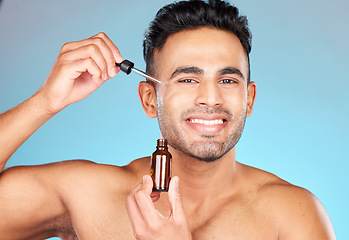 Image showing Skincare, health and portrait of man with serum on face for anti aging and glowing skin on blue background. Beauty, facial and male model with smile and collagen oil product in pipette for treatment.