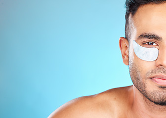 Image showing Portrait, skincare and man with eye mask in studio for beauty, grooming and hygiene wellness on blue background. Face, facial and model relax with eye patch, collagen and skin, cleaning and product