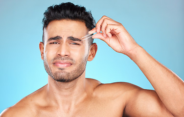 Image showing Beauty, grooming and eyebrow with man and tweezers for self care, hair removal and facial. Pain, focus and shape with model and plucking for cosmetics, treatment and cleaning in blue background