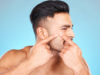 Image showing Man, hands and pop acne of face for skincare, beauty wellness or skin dermatology. Indian man, upset and press facial pimples or blackhead in blue background studio for morning cosmetics care