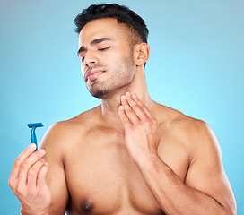 Image showing Skincare, shaving and man with razor in studio on blue background for wellness, beauty and self care. Grooming, facial treatment and male face with worry, concern and anxiety to shave sensitive skin