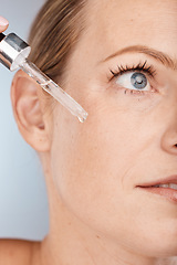 Image showing Face, skincare and serum with a model woman in studio on a gray background to promote a cosmetic product. Facial, beauty and antiaging with a female applying oil to her skin for natural cosmetology