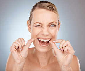 Image showing Smile, wink and woman flossing teeth, morning dental care routine on studio background. Health, wellness and happy woman with dental floss, motivation for cleaning a healthy mouth and fresh breath.