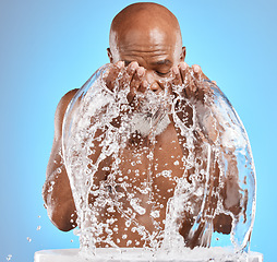 Image showing Water splash, black man and facial skincare on blue background for shower, wellness and clean body care with personal hygiene. Male beauty, studio model and washing face with water drops in bathroom