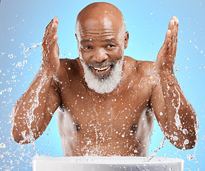 Image showing Water splash, senior and black man cleaning face in studio isolated on a blue background. Skincare, hygiene and retired elderly male from Nigeria bathing or washing for wellness and healthy skin.