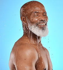 Image showing Studio, water and old man in a shower cleaning his face or body for skincare beauty or wellness on a blue background. Smile, healthy or happy elderly male model washing or relaxing with mock up space