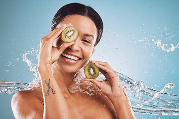 Image showing Skincare, water and portrait of woman with kiwi for natural, organic and healthy beauty products in studio. Dermatology, wellness and girl with fruit, water splash and cosmetics on blue background