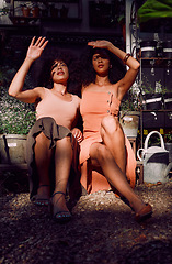 Image showing Hands, sunlight and shade with black woman friends blocking the sun while sitting together at a plant nursery. Spring, gardening and growth with a female and friend outdoor at a flower shop