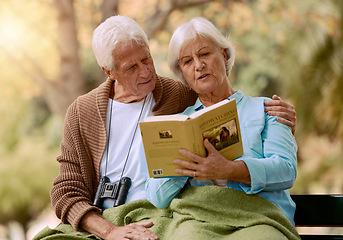 Image showing Park, senior and couple reading a book, relaxing and bonding outdoors with blanket. Love, retirement and elderly man and woman studying literature, story or novel and enjoying quality time together.