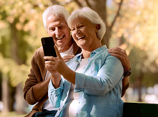 Image showing Senior couple, phone selfie and happy smile, love and relax in outdoor park, summer and social media picture on bench. Elderly man, woman or mobile smartphone, photo and happiness together in nature