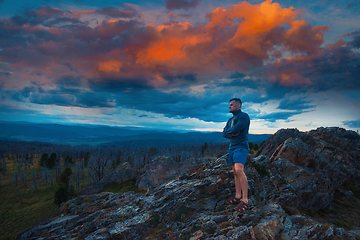 Image showing Man standing on top of cliff with fantastic sunset