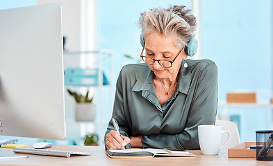 Image showing Senior woman, writing and schedule in office with music headphones at desk, reading or focus. Elderly secretary, receptionist or communication executive at table with notebook, pc or listen to radio