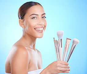 Image showing Skincare, beauty and makeup brush for portrait, cosmetics and foundation for glow, smile and happiness on face with blue studio background. Aesthetic Colombia model with beautician or makeover tools
