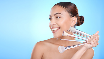 Image showing Beauty, woman with makeup and brush in hand with cosmetic tools advertising, foundation and powder against blue background. Model with smile for wellness, skincare and face cosmetics care mockup.