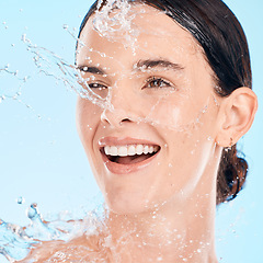 Image showing Face, woman and water for skincare, natural beauty and organic facial against blue studio background. Young female, girl and liquid drops for hygiene, detox and wet for washing, shower and smile.