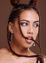 Image showing Makeup, hair and woman biting braid with edgy hairstyle and beauty on a brown studio background. Trendy, cosmetics and cosmetic haircare with braided hair style and cool eyeliner on a studio backdrop