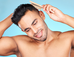 Image showing Hair care, beauty and man brushing hair, marketing barber and salon care against a blue background in studio. Self care, grooming and model thinking of hairstyle with a brush for advertising