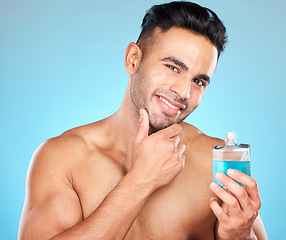 Image showing Beauty, cosmetics and man with cologne in studio on blue background for wellness, self care and luxury. Skincare, grooming and Indian male model with perfume, fragrance and scent in bottle