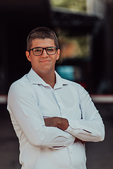 Image showing A successful businessman in a white shirt, with crossed arms, poses outdoors, confident expression on his face.