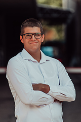 Image showing A successful businessman in a white shirt, with crossed arms, poses outdoors, confident expression on his face.