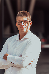 Image showing A successful businessman in a white shirt, with crossed arms, poses outdoors, confident expression on his face.