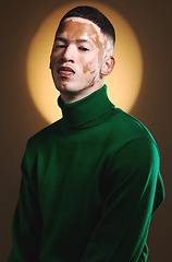 Image showing Vitiligo, portrait and male fashion model in stylish, trendy and fashionable outfit on a brown studio background. Backdrop, edgy and artistic man posing in green clothing with a cool attitude