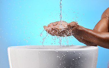 Image showing Black man, water splash and washing hands on blue background in studio hygiene maintenance, bacteria cleaning or healthcare wellness. Zoom, model and wet sink for skincare grooming in house bathroom
