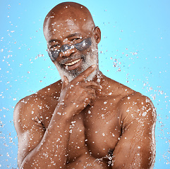 Image showing Water, shower and skincare with a model black man in studio on a blue background for hygiene or hydration. Water splash, wet and beauty with a senior man in the bathroom for antiaging treatment