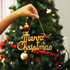 Image showing Woman hand and festive decoration, Christmas sign with tree in the background in home living room. Female Hands with icon, festive holiday, celebration and xmas decorations, creative and . gold