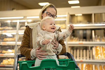 Image showing Caucasian mother shopping with her infant baby boy child choosing products in department of supermarket grocery store.