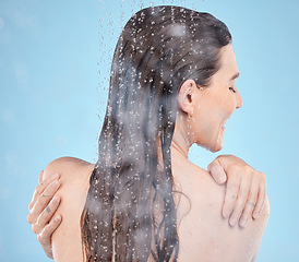 Image showing Back, water and woman shower, skincare and washing for wellness, body care and health on blue studio background. Young female, girl and wet for natural beauty, cleaning and liquid drops to relax.